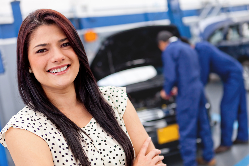 Woman at a car garage getting mechanical service Woman at a car garage getting mechanical service