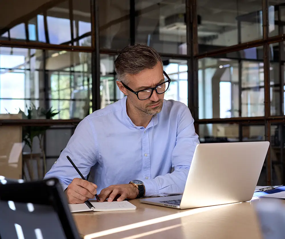 Man watching at the computer and writing a note